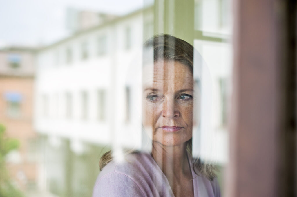 Job search for woman over 50 looking out of window.